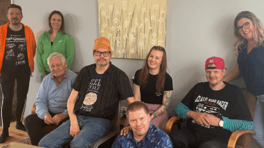 Perhoslehdon työntekijöitä ja asiakkaita rivissä.