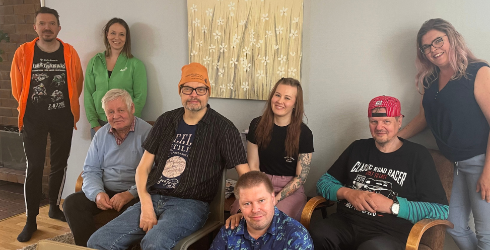 Perhoslehdon työntekijöitä ja asiakkaita rivissä.