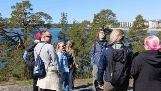 Työntekijät nauttivat luonnosta aurinkoisella kalliolla.