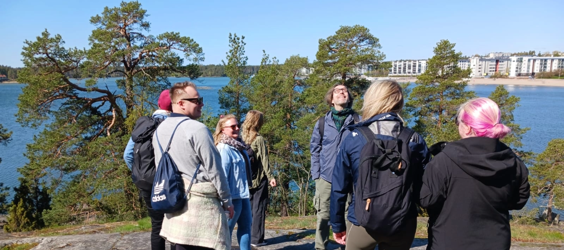 Työntekijät nauttivat luonnosta aurinkoisella kalliolla.