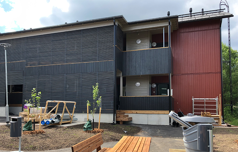 Kaksikerroksinen ruskea rivitalo.