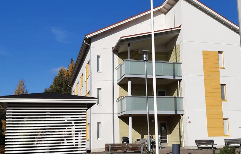 Valkoinen kerrostalo, jossa harmaat parvekkeet.