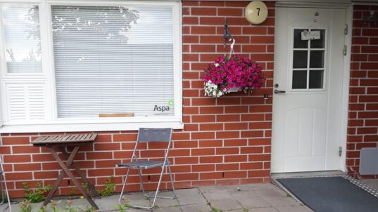 Punatiilisen talon seinä ja valkoinen ovi.