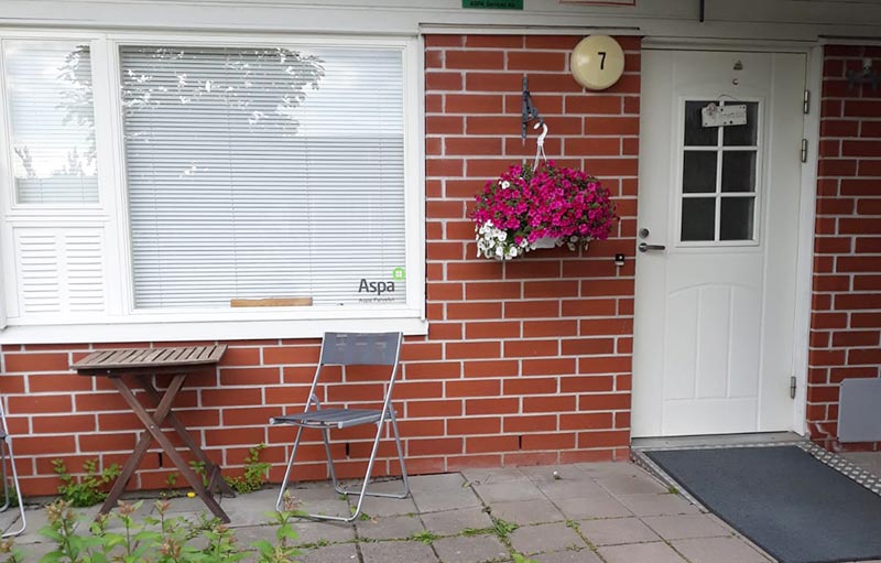 Punatiilisen talon seinä ja valkoinen ovi.