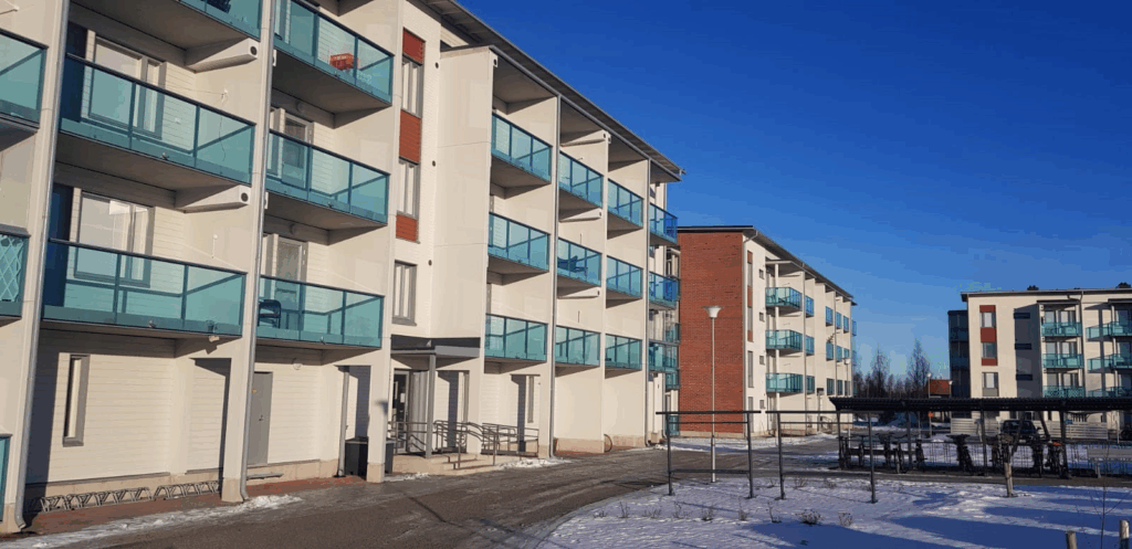 Valkoinen kerrostalo punatiilipäädyin.