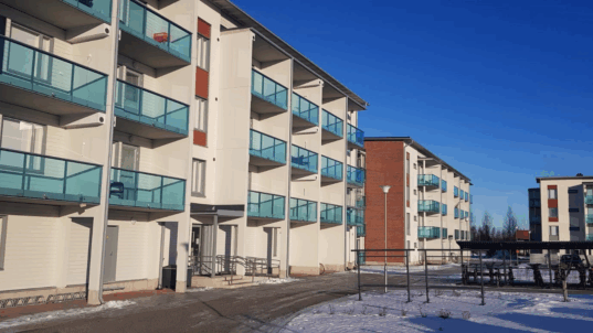 Valkoinen kerrostalo punatiilipäädyin.