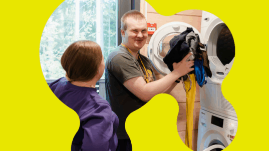 Aleksi laittaa pyykkiä pesukoneeseen.