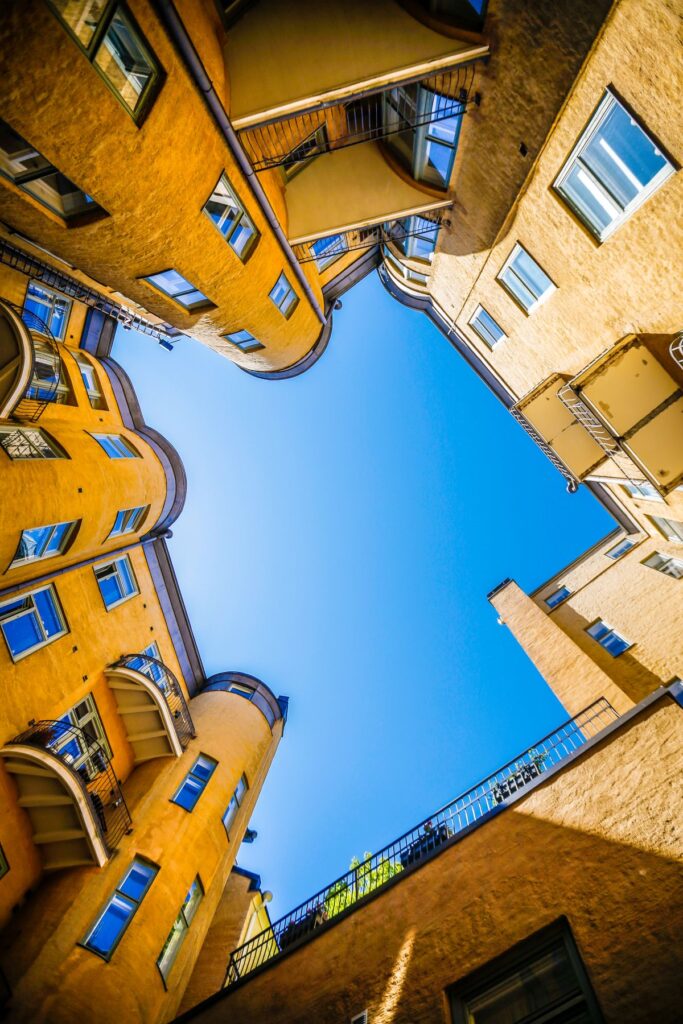 Keltaisten kerrostalojen ympäröimä sisäpiha ja sininen taivas.