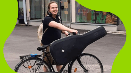 Mies polkupyörän ja kitaran kanssa.