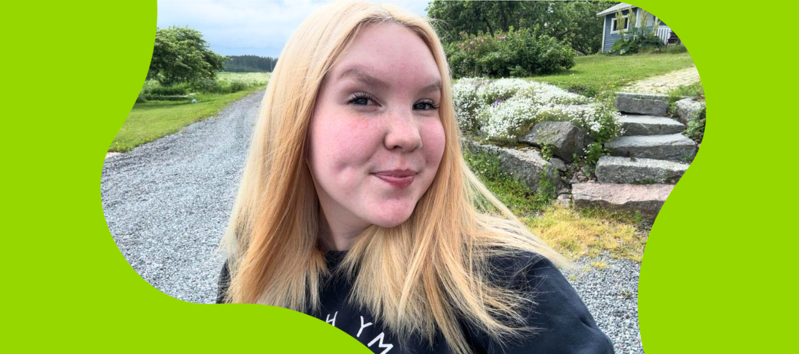 Vaaleahiuksinen nainen hymyilee ulkona.