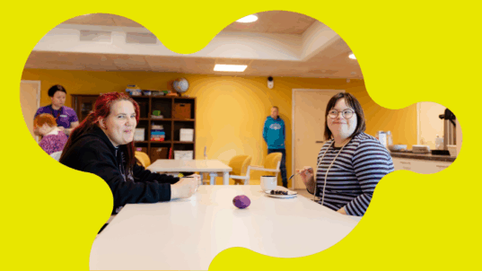 Kaksi nuorta naista istuvat kahvipöydän ääressä.