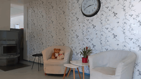 Oleskelutila, jossa tuolit ja kello seinällä.