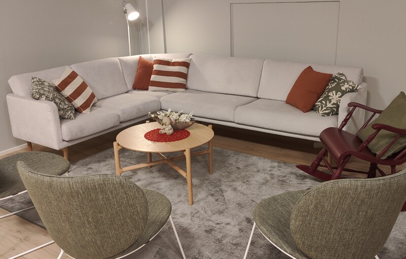 Valkoinen sohva, sohvapöytä ja tuoleja.