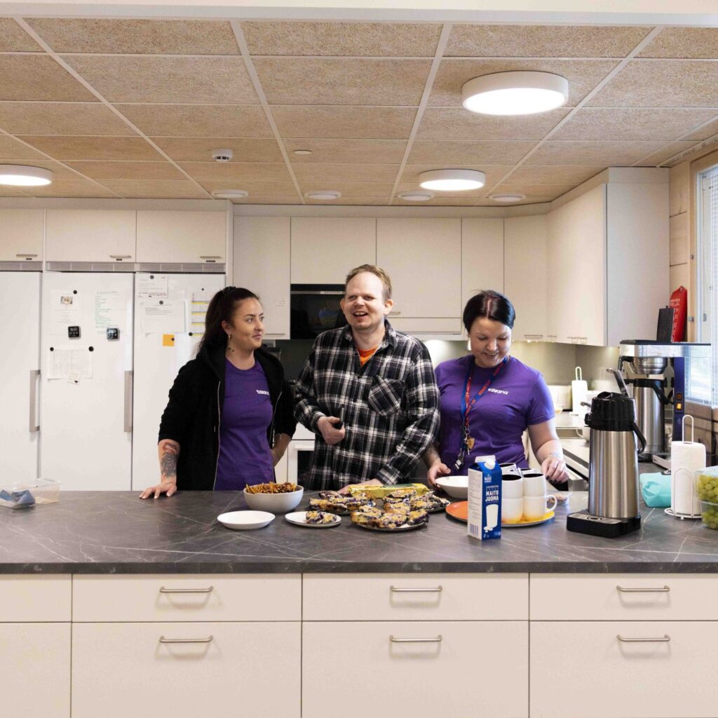 Kaksi Tavanan työntekijää ja asiakas ottamassa välipalaa.