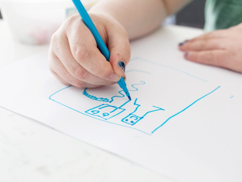 Käsi piirtää sinisellä tussilla.