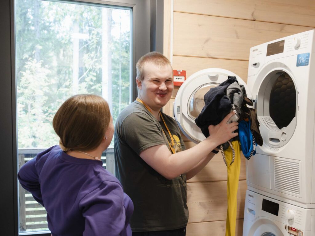 Tavanan asiakas laittamassa pyykkiä pesukoneeseen.