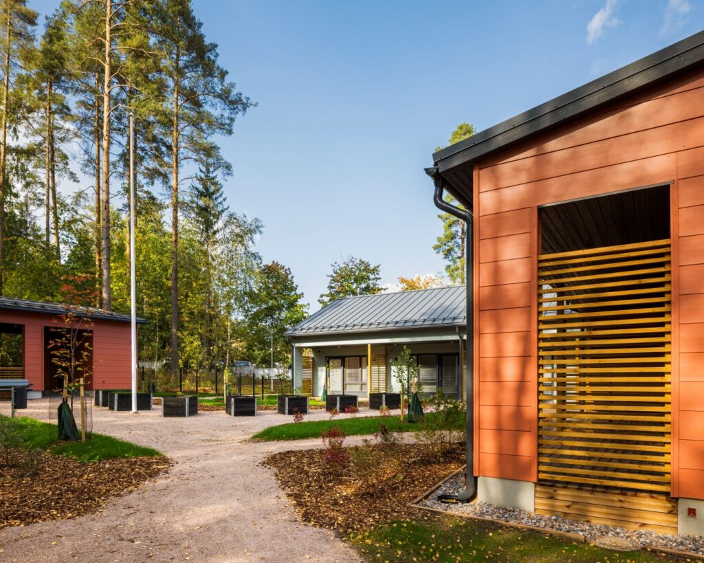 Hirsirakennuksia ja piha, jossa on istutuslaatikoita.