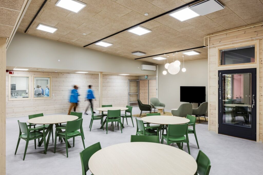 Pyöreitä pöytiä ja vihreitä tuoleja.