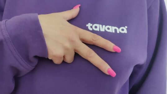 Violetti tavana-paita, jonka päällä käsi viittomassa tavanaa.