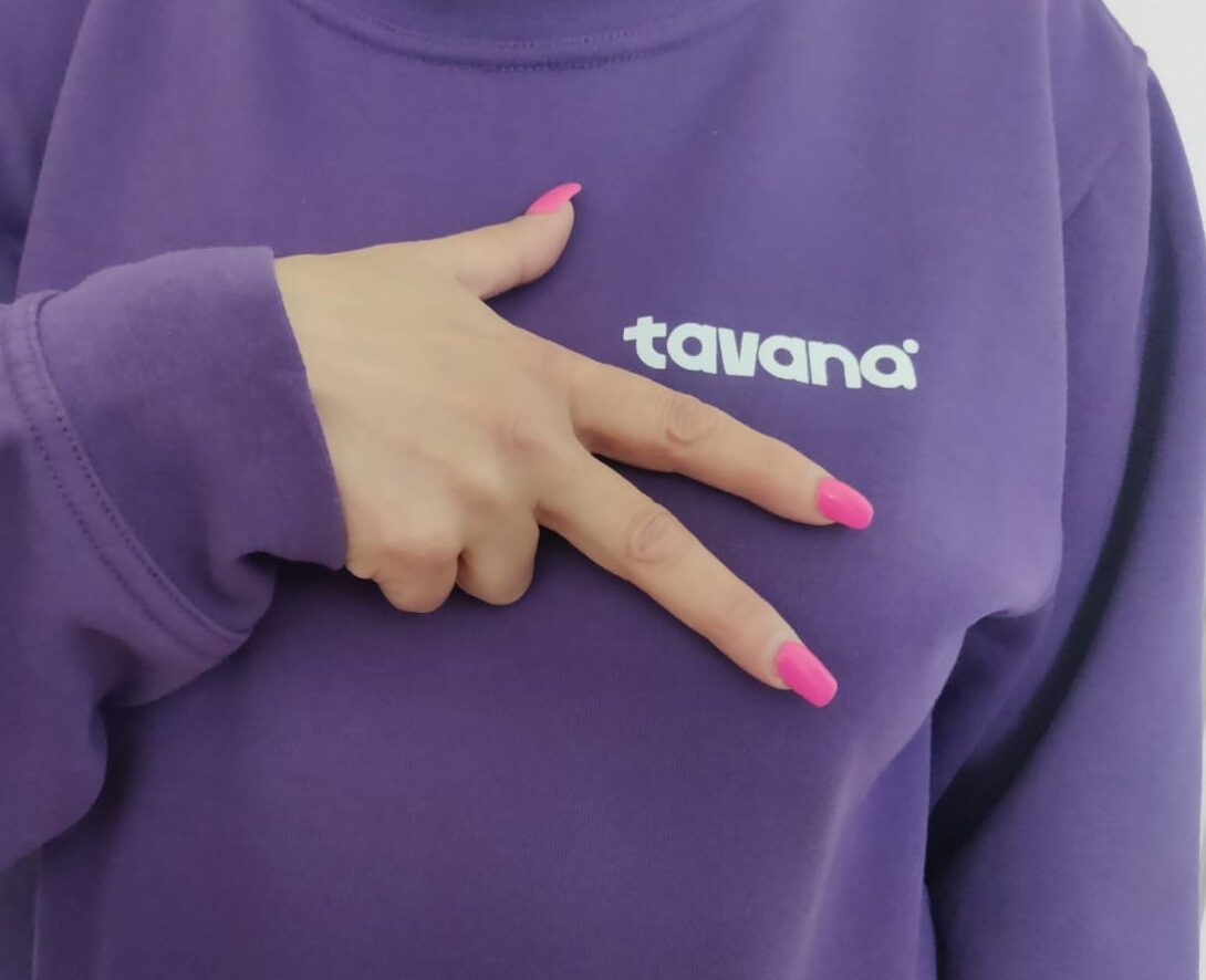 Violetti tavana-paita, jonka päällä käsi viittomassa tavanaa.