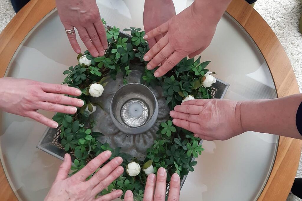 Monta kättä laskettu seppeleen päälle.