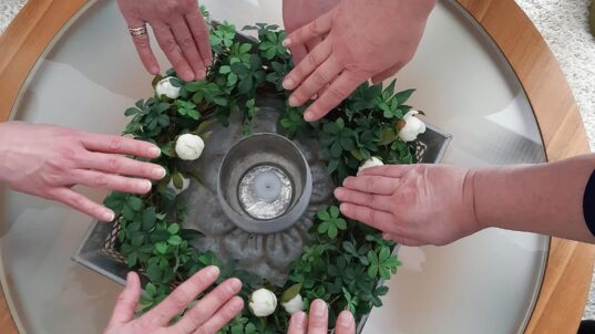 Monta kättä laskettu seppeleen päälle.